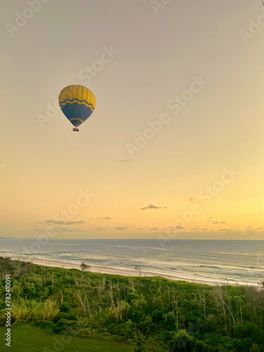 Hot air balloon in the morning sky across Australia, with the coast and rolling sea in the background