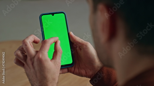 Manager fingers zooming chromakey cellphone indoors. Man working green screen photo