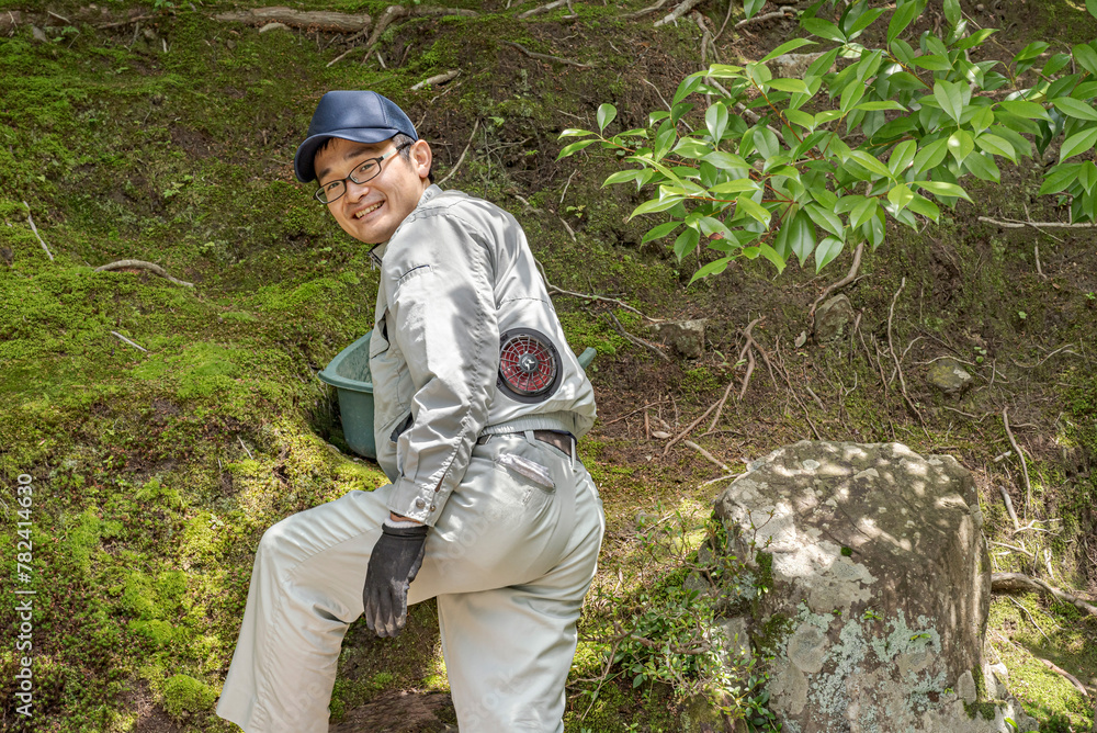 Portrait of a smiling Japanese gardener.
Worker using a special vest with included fan to keep himself fresh.
