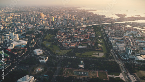 Modern buildings at cityscape of Manila city aerial. Harbor town at ocean bay with urban streets and roads. Philippines landmark of designed landscape and skyscrapers. Cinematic soft light drone shot