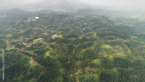 Asia mist mounts peaks aerial view: green hill foggy skyline at nobody landscape in Mayon, Philippines. Small mountains with grass, trees, valleys. Asian wild nature at cloudy day. Footage drone shot