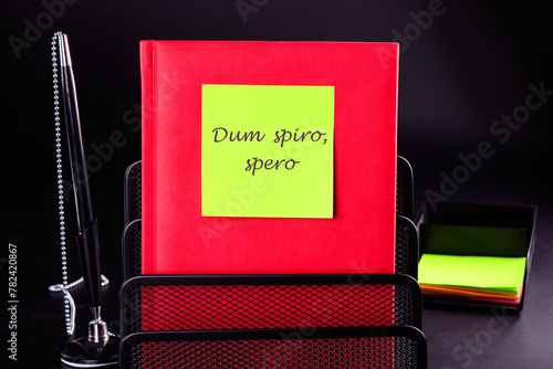 Dum Spiro Spero - latin phrase means While I Breath, I Hope. on a yellow sticker on a red notebook. Concept photo photo
