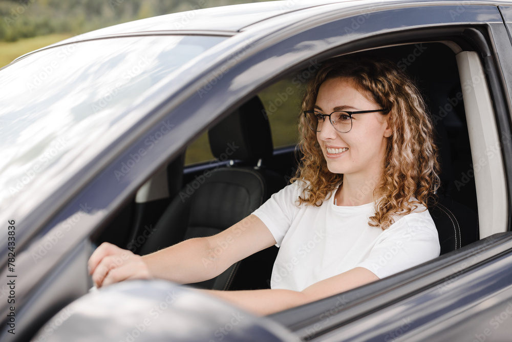 young beautiful smiling woman driving car, attractive caucasian woman in white t-shirt
