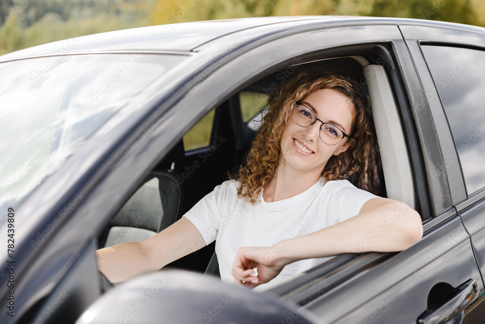 young beautiful smiling woman in car looking straight to camera, attractive caucasian woman in white t-shirt young beautiful smiling woman in car looking straight to camera, attractive caucasian woman in white t-shirt