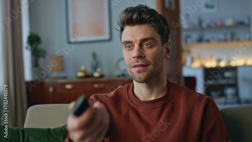 Closeup man watching show on tv at home. Portrait smiling guy switching channel