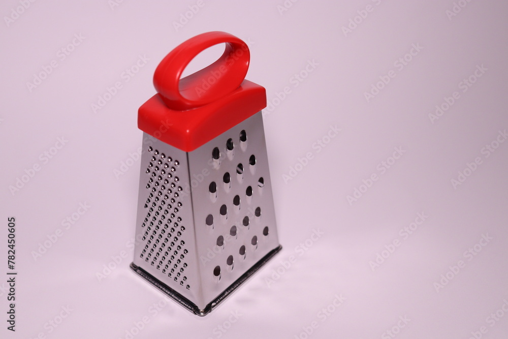 a small vegetable grater with a red handle on a white background a small vegetable grater with a red handle on a white background