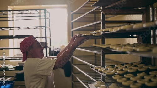 Happy baker places the bread trays on the shelf for fermentation. photo