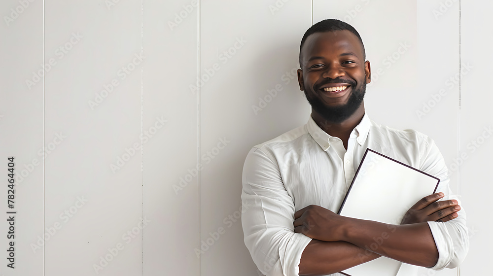 a man standing in front of a white wall holding a folder and a pen in his hand and smiling a man standing in front of a white wall holding a folder and a pen in his hand and smiling
