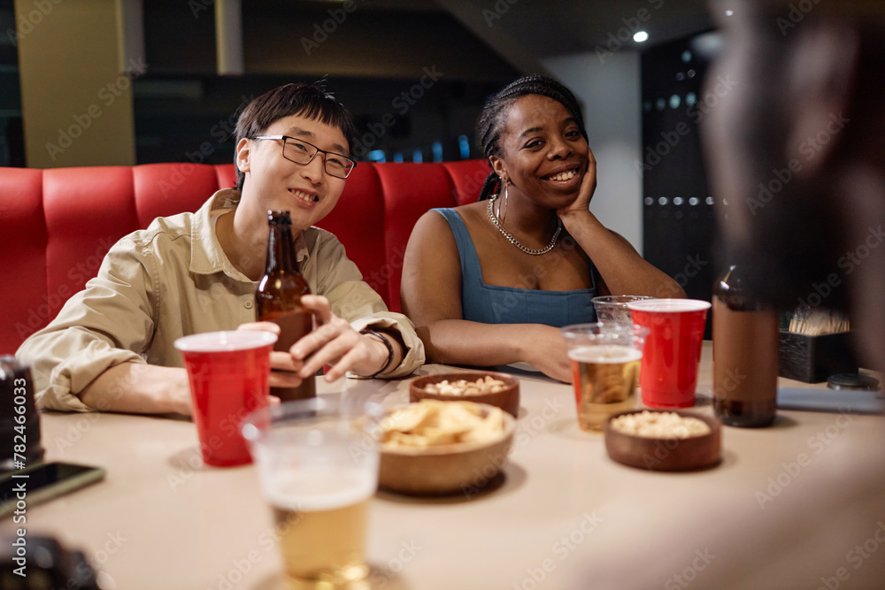 Candid portrait of two young people sitting at table in diner enjoying conversation with friends Candid portrait of two young people sitting at table in diner enjoying conversation with friends