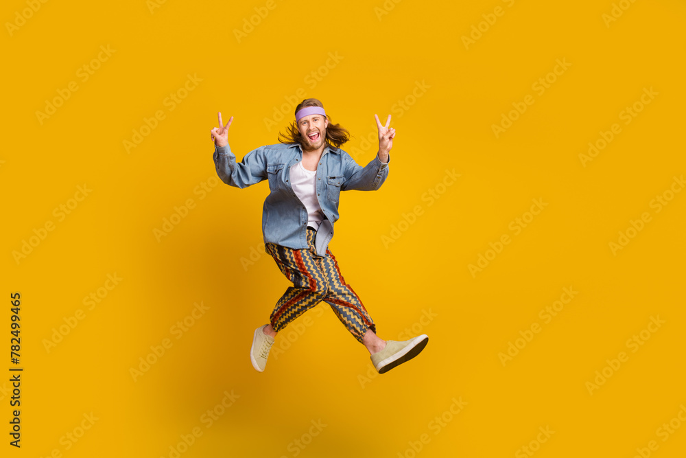 Full body portrait of cool young man jump show v-sign empty space wear denim shirt isolated on yellow color background Full body portrait of cool young man jump show v-sign empty space wear denim shirt isolated on yellow color background