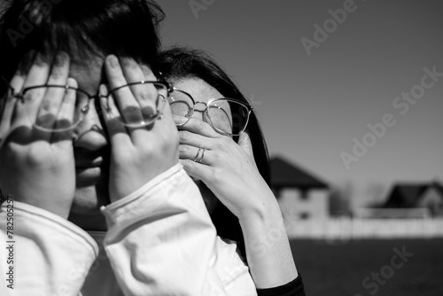 Conceptual portrait of a two women in eyeglasses. Young attractive women covering her faces with a her hands  © PumpedVisuals