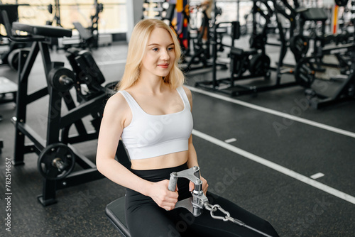 young athletic caucasian woman trains in fitness gym, thrust in block simulator, blonde girl in white top and black leggings, healthy lifestyle concept