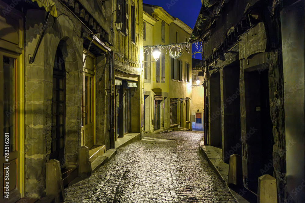 A narrow alley illuminated at night in the La Cite' old town inside the medieval walls of the castle in the historic city of Carcassonne, France.