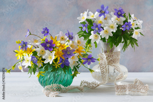 Two bouquets of spring blue, purple, white and yellow flowers in vases on the table, a beautiful still life.