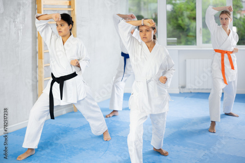 Female athletes have taken starting position and studying and repeating sequence of punches and painful techniques in karate kata technique. Oriental martial arts, training and obtaining black belt