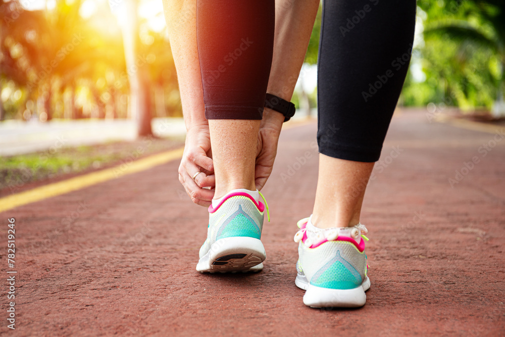 Runner woman tying up laces of shoes, getting ready to run for cardio and weight loss Runner woman tying up laces of shoes, getting ready to run for cardio and weight loss