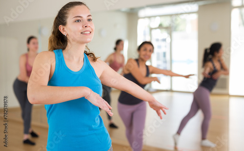 Portrait of cheerful active girl exercising dance moves in fitness studio