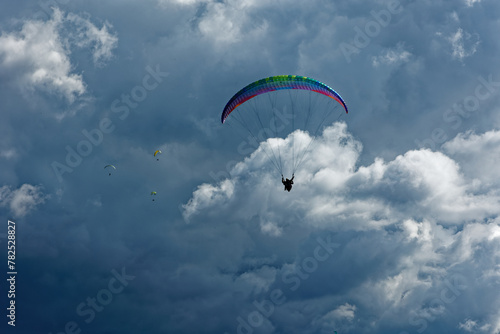 People enjoy the extreme sport of paragliding. Outdoor living in the blue sky. Incredible nature and views. Adventures and adrenaline with parachute. Travel destination Norma Latina Italy. Summer 