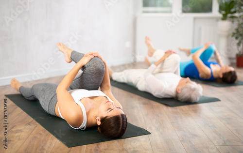 Group of women doing yoga in a fitness center practice the Pawana Muktasana pose during a workout, which has a profound effect .on the body