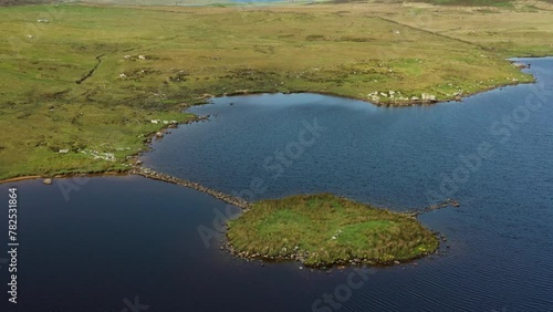 Eilean Domhnuill islet in Loch Olabhat, N. Uist, Scotland. Important 5000 year prehistoric Neolithic early crannog habitation site and causeway. View to S.W. Video aerial drone moving back and up photo