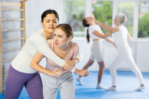Self-defense class - woman learns to fight back an attacking man under the guidance of a trainer