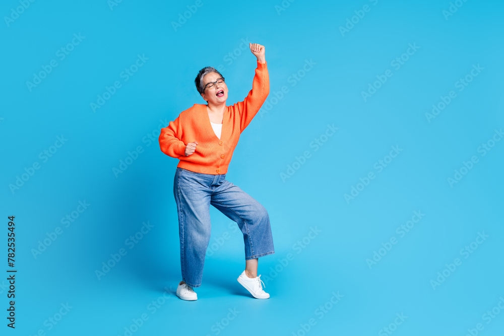 Full body photo of lovely senior lady dancing have fun dressed stylish orange garment isolated on blue color background