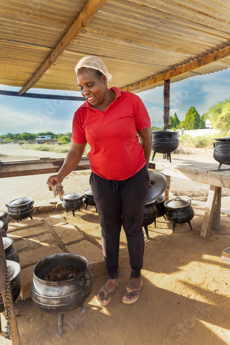 woman african street vendor selling cooked setswa food from a large pot on the side of the highway photo