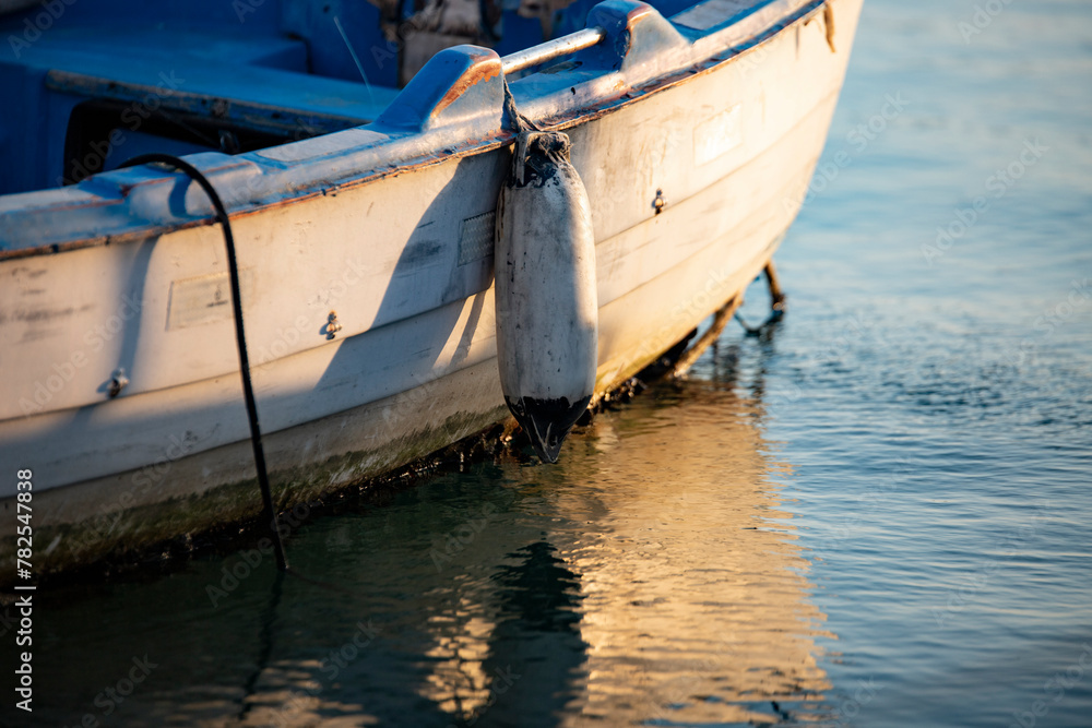 Wooden boat on the water in the port. Fishing boat on the water at sunset. Close-up of a fishing boat. Wooden boat on the water in the port. Fishing boat on the water at sunset. Close-up of a fishing boat.