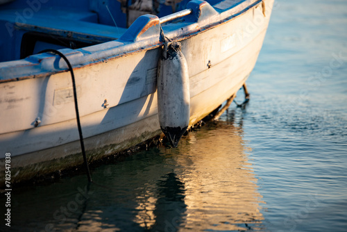 Wooden boat on the water in the port. Fishing boat on the water at sunset. Close-up of a fishing boat. © Caneritir