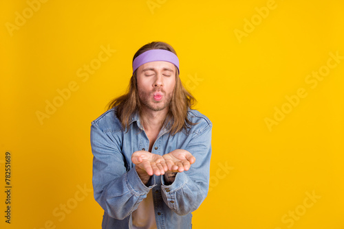 Photo portrait of attractive young hippie man send air kiss wear trendy denim outfit isolated on yellow color background