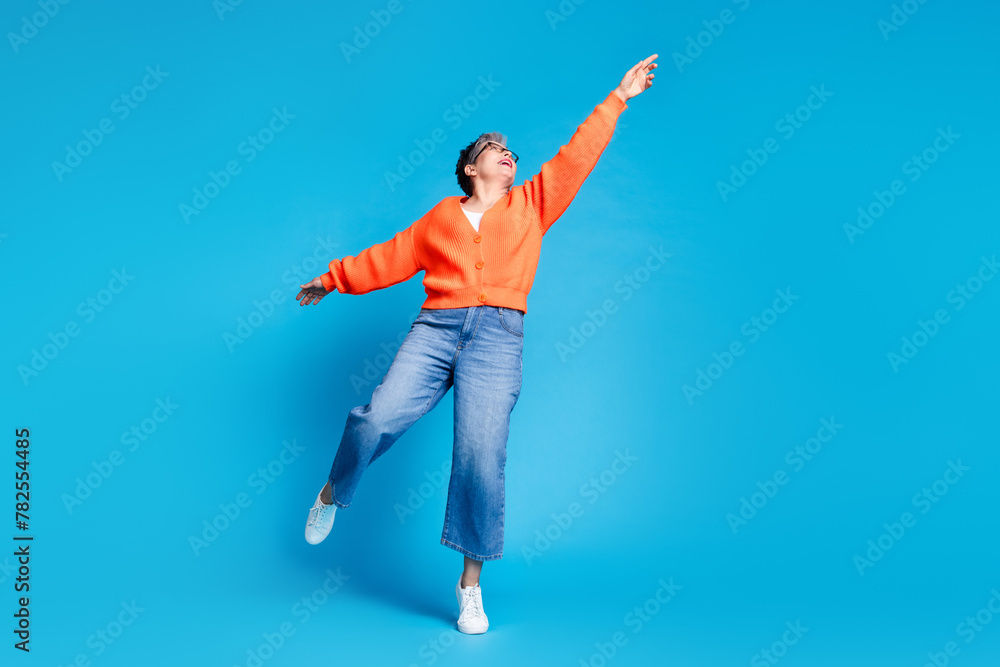 Full body photo of lovely senior lady hanging pose dressed stylish orange garment isolated on blue color background