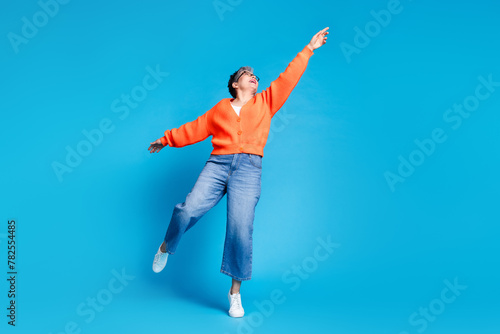 Full body photo of lovely senior lady hanging pose dressed stylish orange garment isolated on blue color background