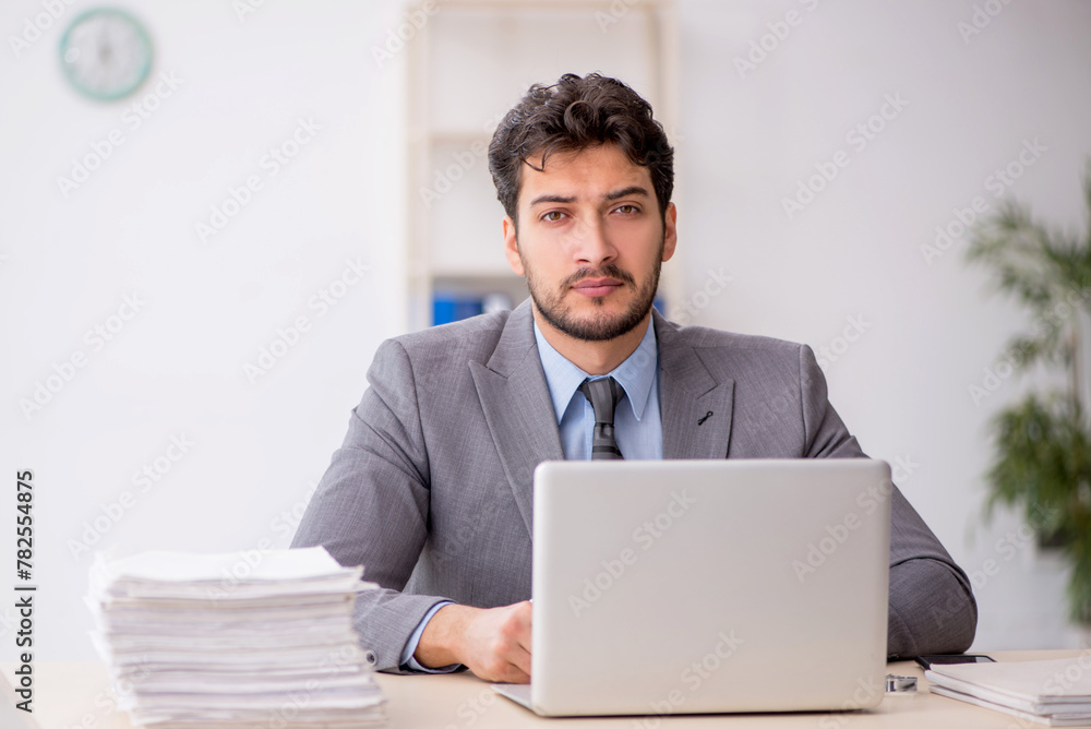Young male employee and too much work in the office Young male employee and too much work in the office