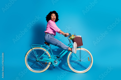 Fototapeta Naklejka Na Ścianę i Meble -  Full length side profile photo of impressed woman wear pink shirt driving bicycle astonished staring isolated on blue color background