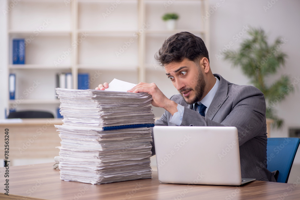 Young male employee and too much work in the office Young male employee and too much work in the office