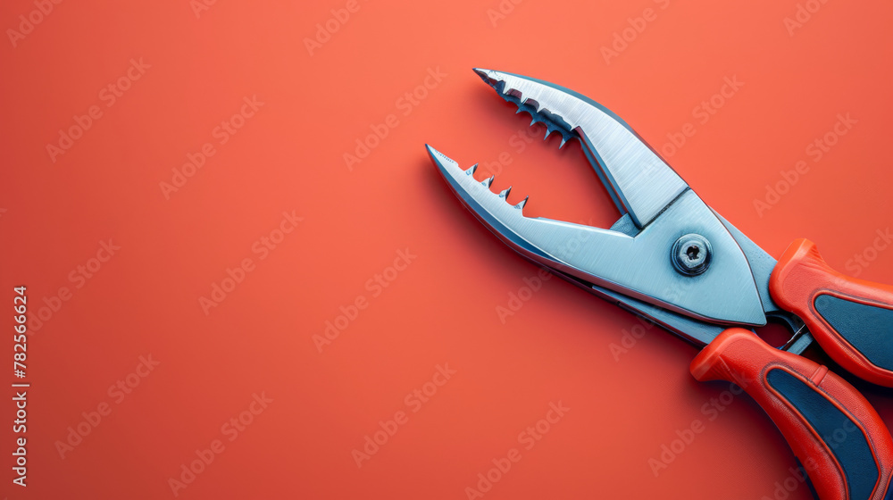 Stainless steel pliers with red and black rubber grips isolated on a vivid red background. Stainless steel pliers with red and black rubber grips isolated on a vivid red background.