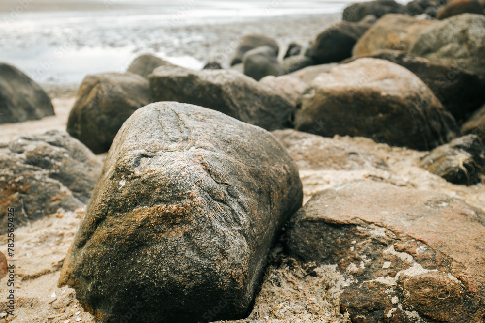 Stone groyne on beach background.Stone boulders on the beach at low tide.Marine photo wallpaper.Nature of the North Sea coast. Frisian Islands of Germany. Rest on the sea. Stone groyne on beach background.Stone boulders on the beach at low tide.Marine photo wallpaper.Nature of the North Sea coast. Frisian Islands of Germany. Rest on the sea.