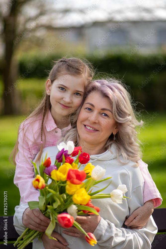 Mother and daughter smiling with tulips in park