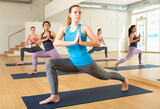 Glad positive women exercising during yoga class in modern studio