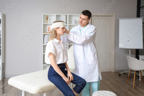 Male doctor bandaging woman s head with brain concussion in clinic