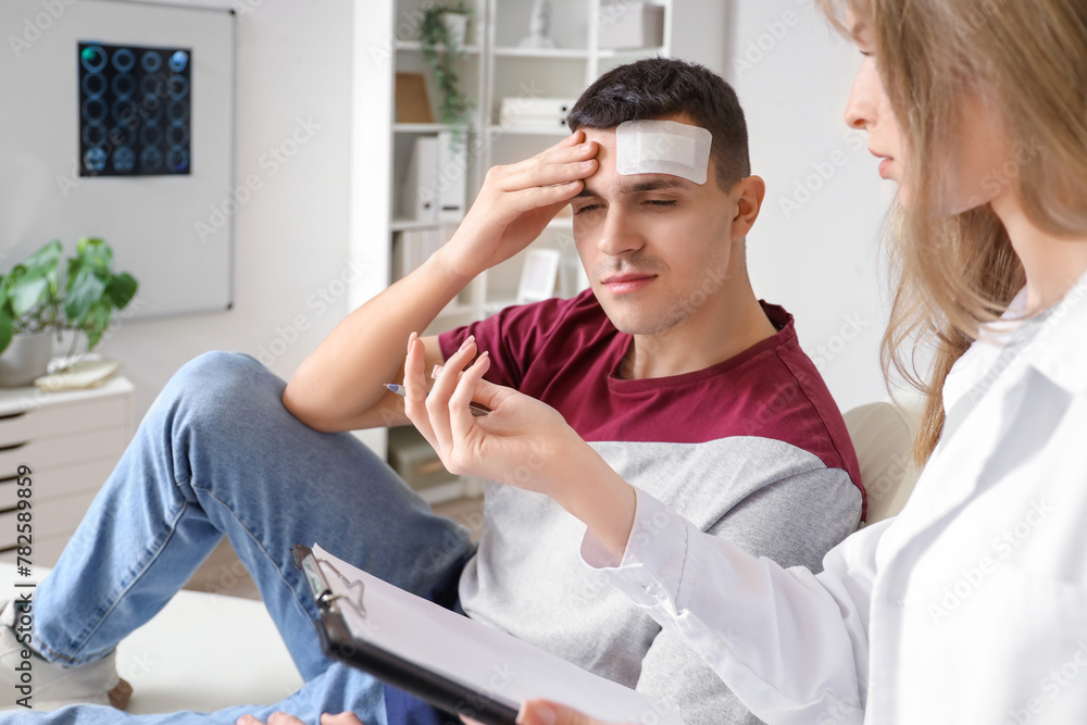 Female doctor examining man with brain concussion in clinic Female doctor examining man with brain concussion in clinic