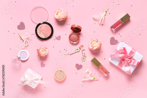 Makeup products with earrings, gift boxes and flowers on pink background