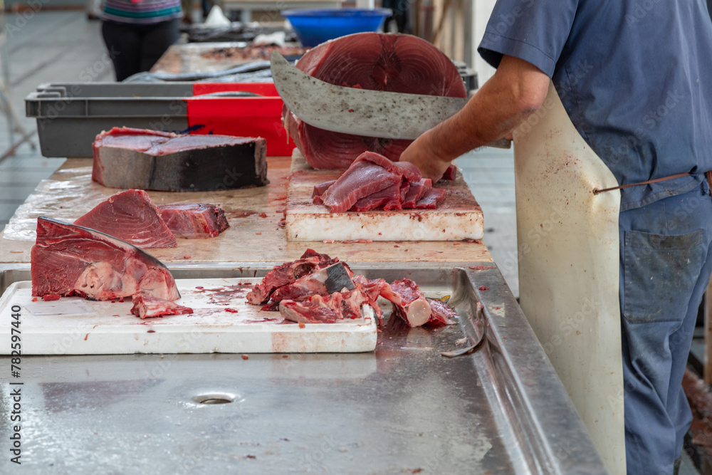 Fish Monger Cutting Tuna Steaks From a Whole Fish With a Large Cleaver in a Fish Market in Funchal, Madeira, Portugal Fish Monger Cutting Tuna Steaks From a Whole Fish With a Large Cleaver in a Fish Market in Funchal, Madeira, Portugal