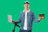 Male courier with coffee, laptop and kick scooter on green background