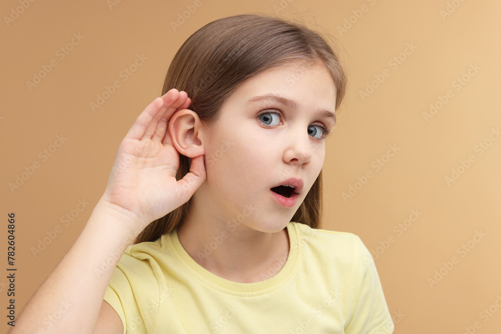 Little girl with hearing problem on pale brown background Little girl with hearing problem on pale brown background