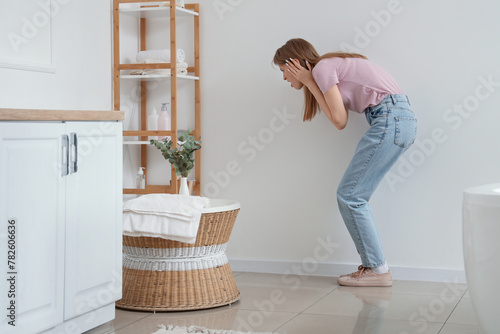 Shocked young woman looking at mold on wall in bathroom