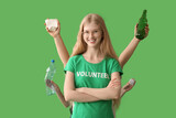 Female volunteer and hands with bottles and paper on green background