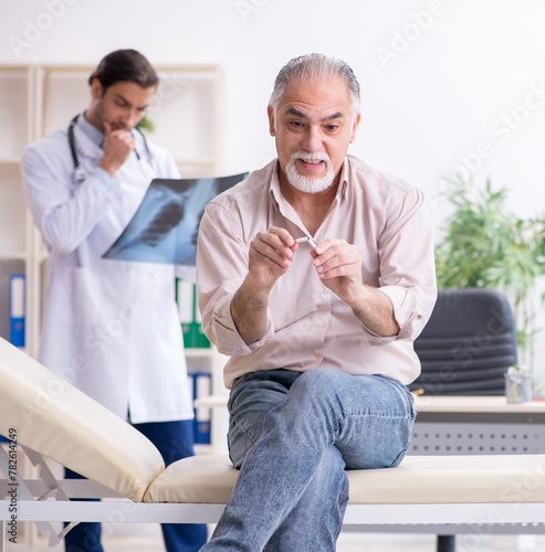 фотографія Young male doctor and old patient in antismoking concept