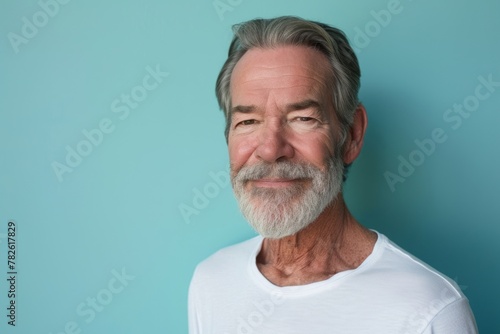 Portrait of a senior man with grey beard against a blue background