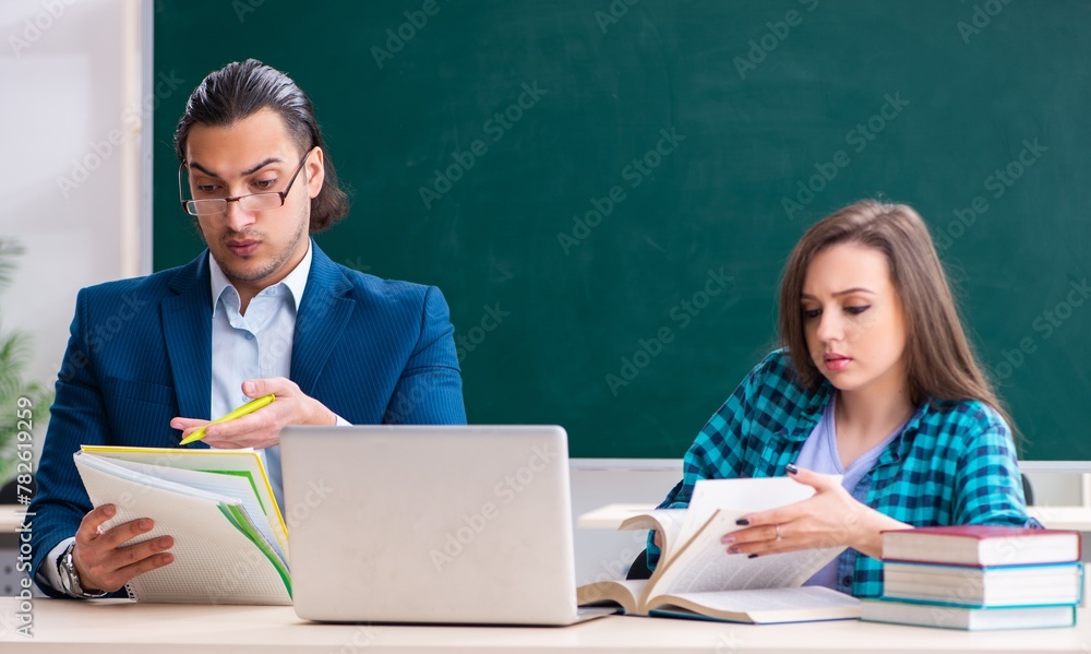 Young handsome teacher and female student in the classroom Young handsome teacher and female student in the classroom